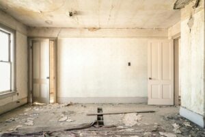 Dilapidated room with damaged floors and walls, illustrating the types of issues renovation loans can help address after a home inspection.